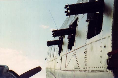 Side view of AC-47 aircraft gunship with three miniguns protruding from windows.
